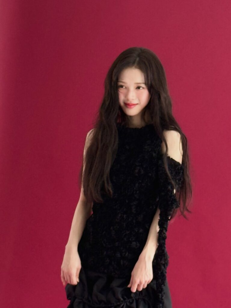 赤い背景の前で黒いワンピースを着たノ・ジョンウィさんが微笑んでいる写真