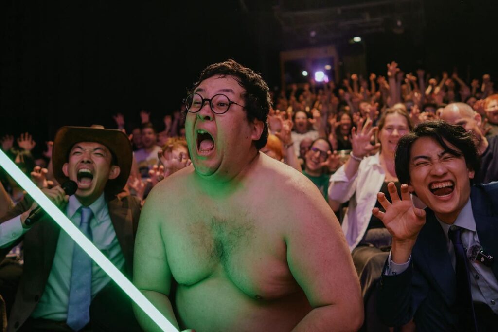 ドイツの映画祭会場で、光る棒を持ったぐんぴぃさんを中心に観客たちが熱狂している様子