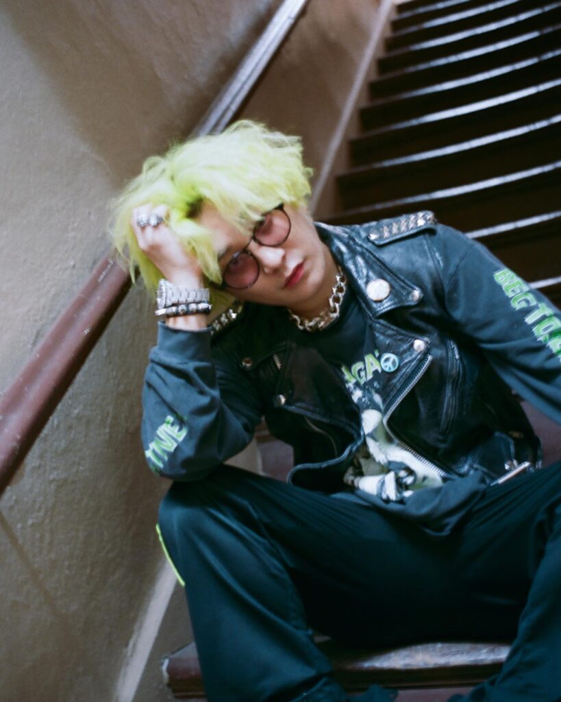 緑がかった金髪で階段に座るFukaseさんの写真。
