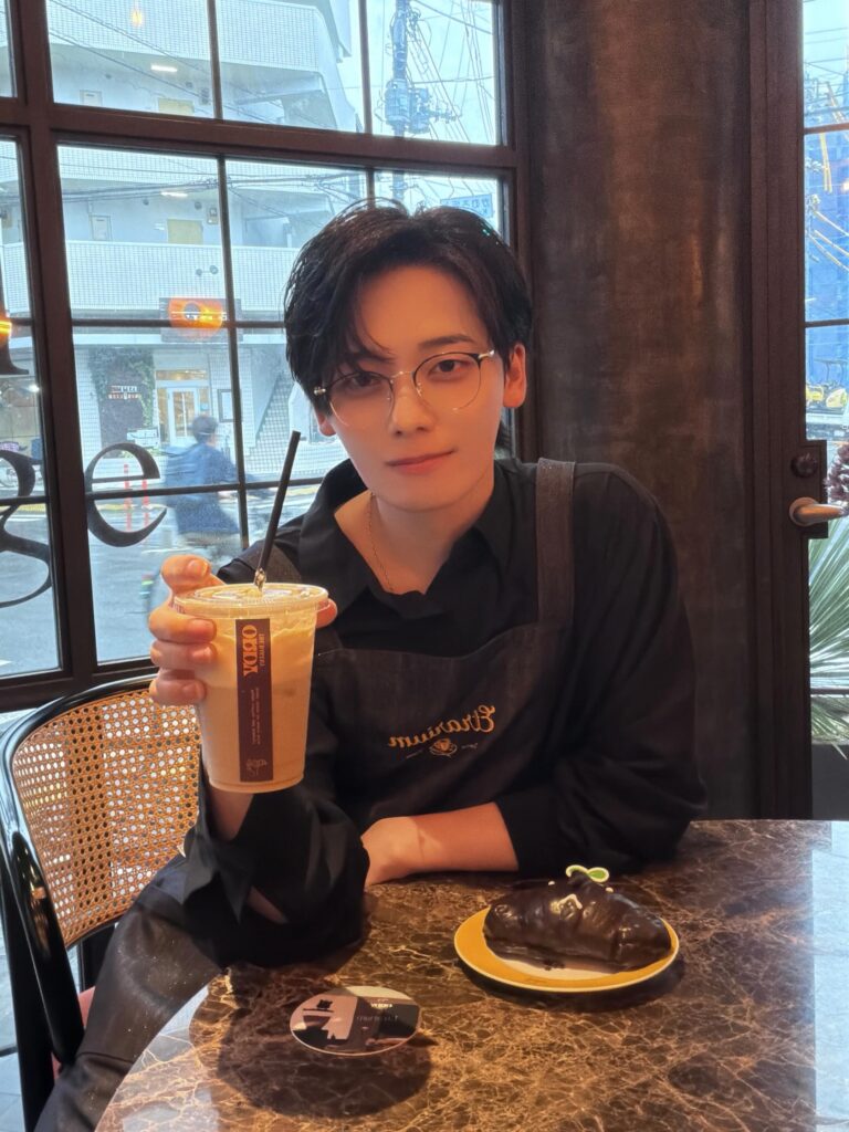 カフェでアイスドリンクを手にカメラを見つめるみやかわくん