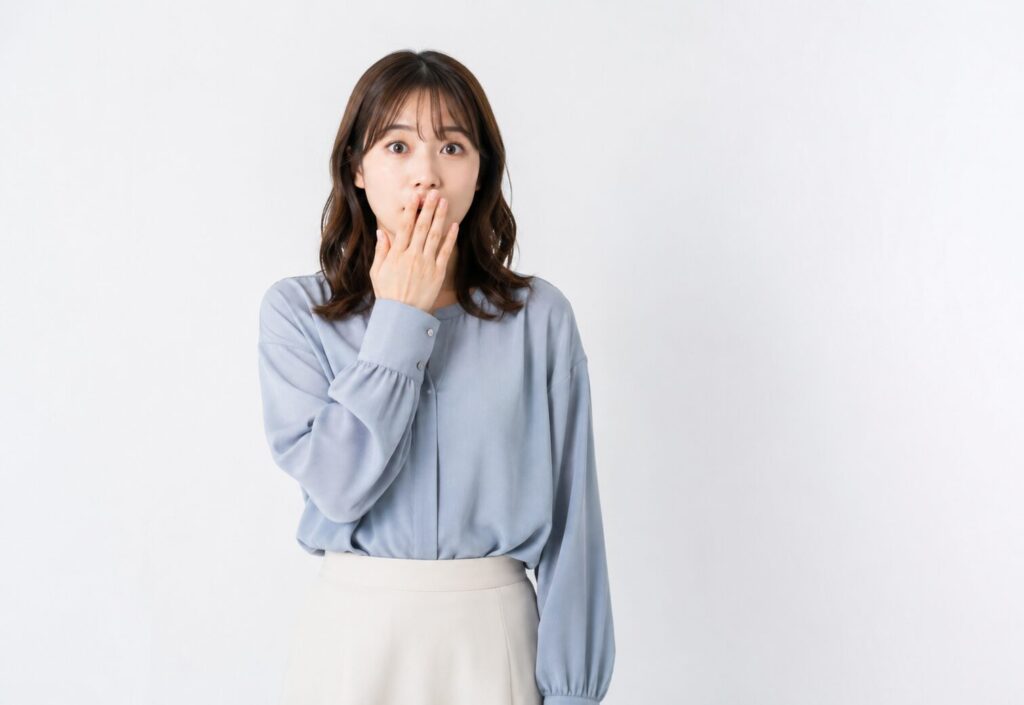驚いた表情で口元に手を当てる女性のイメージ画像