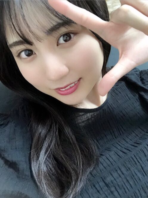 カメラに向かって微笑みながら、顔の横で指を広げたポーズをとる賀喜遥香さん