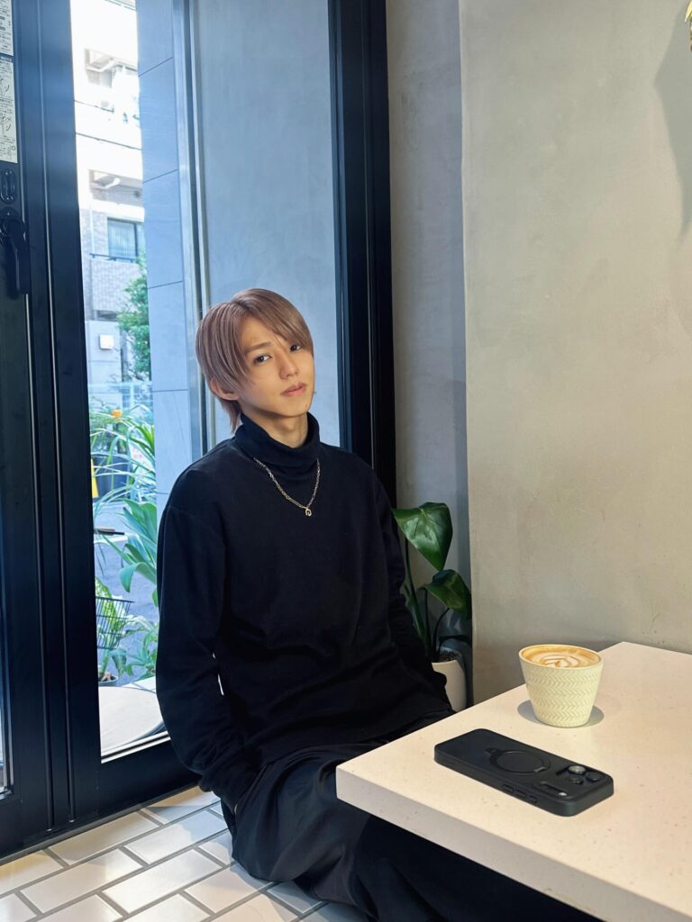 金髪姿で屋内のテーブル席に座るタロー社長